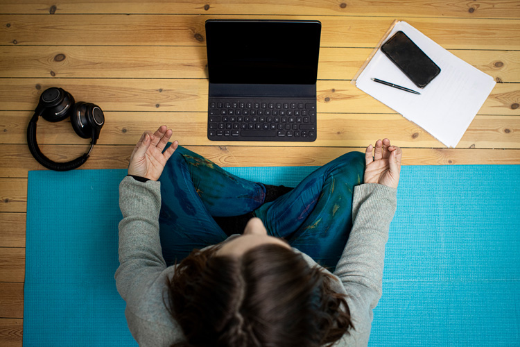 Kvinna mediterar framför datorn.